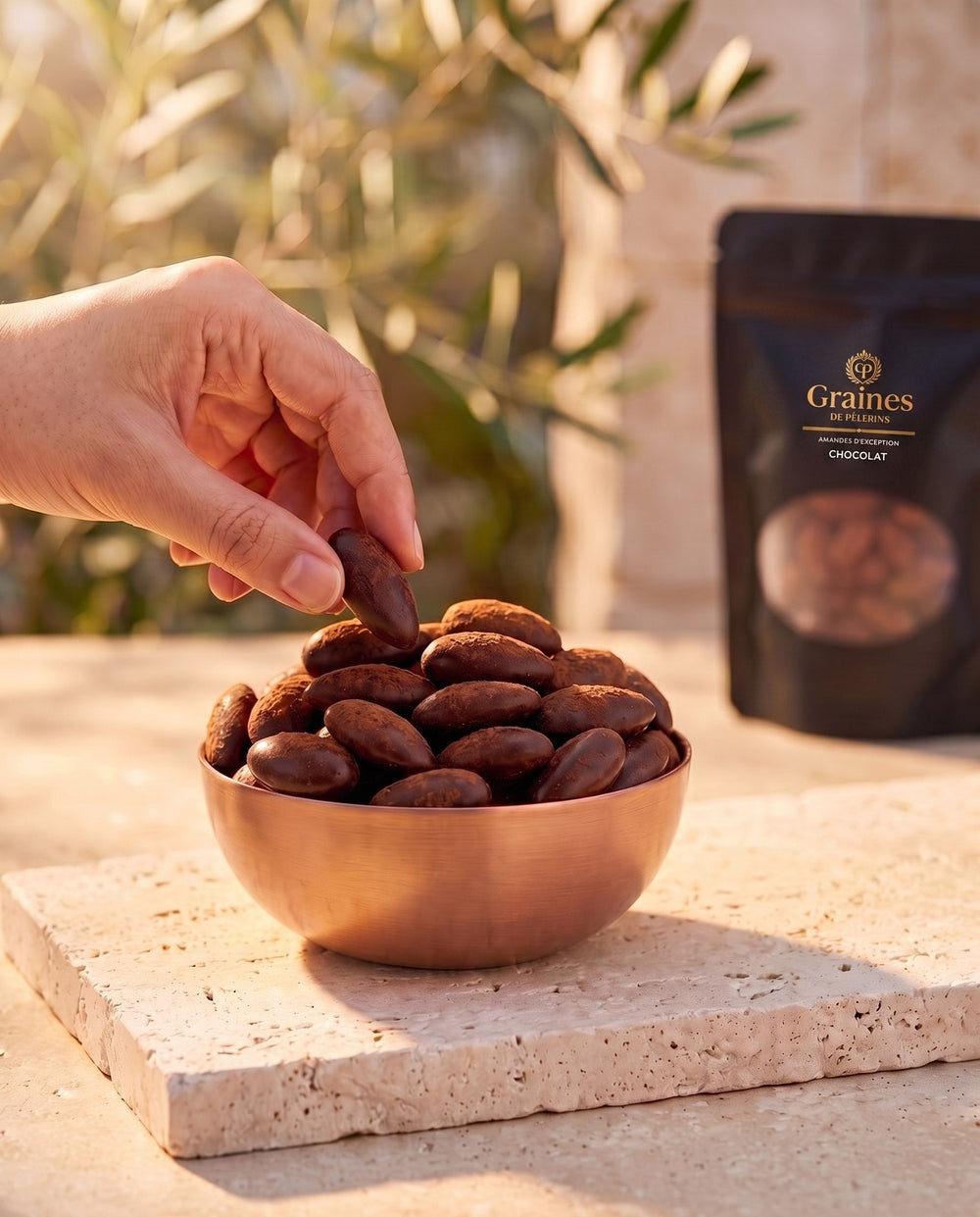 Amande Chocolat, moment chocolat chaud, bol de cuivre rempli d'amandes au chocolat sur pierre claire