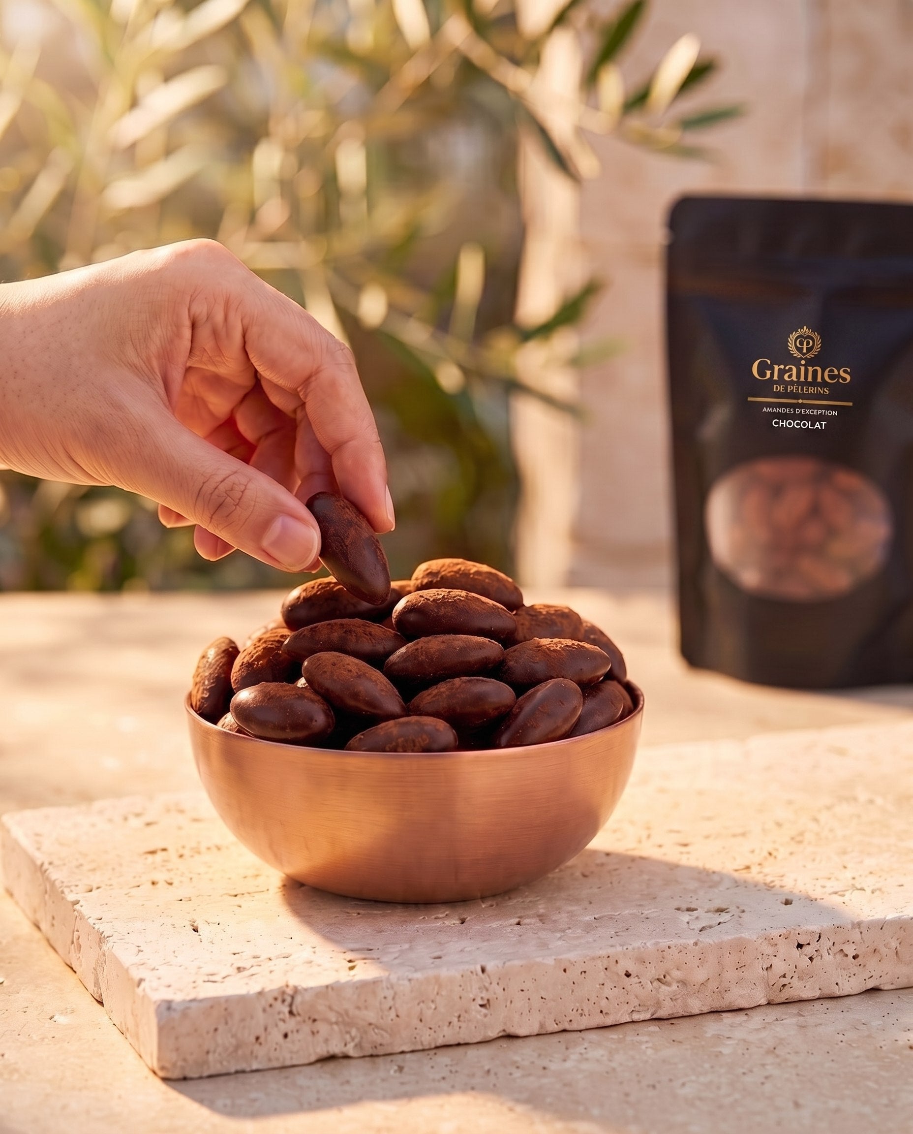 Amande Chocolat, moment chocolat chaud, bol de cuivre rempli d'amandes au chocolat sur pierre claire
