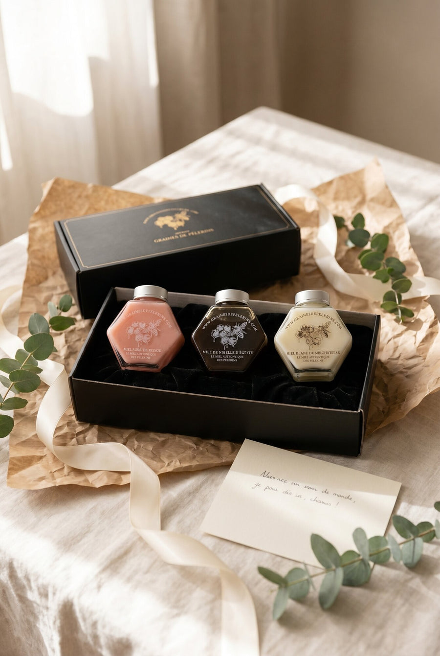 Coffret Découverte ouvert avec trois miels rares, ruban et eucalyptus, lumière d'été — Graines de Pèlerins
