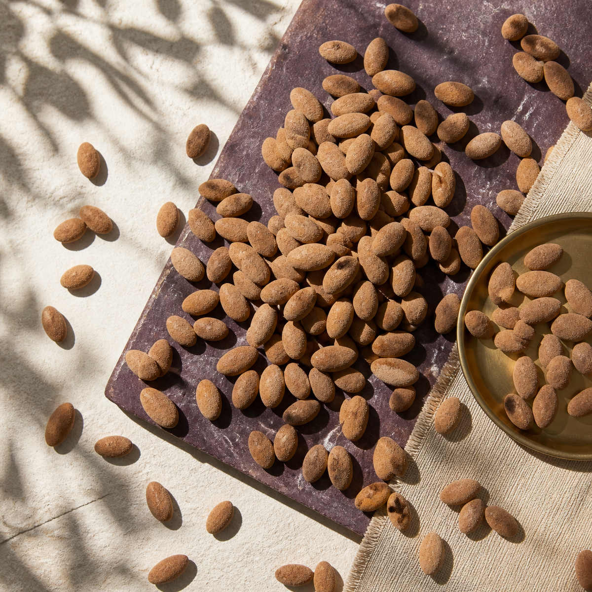 Amandes Chocolat dispersées sur une plaque aubergine dans une nature morte vue du dessus