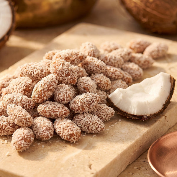 Amande Noix de Coco, macro amandes longues effilées et copeaux de coco mats sur pierre claire, sans emballage