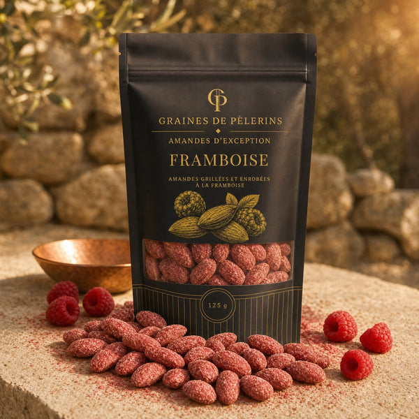 Amande Framboise, sachet Graines de Pèlerins debout sur pierre travertin, poudre de framboise mate et framboises fraîches
