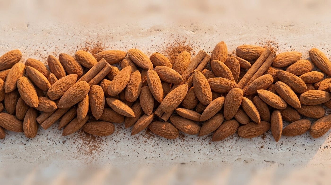 Amande Cannelle, bande texture amandes longues effilées et bâtons de cannelle sur pierre claire, variante fondu