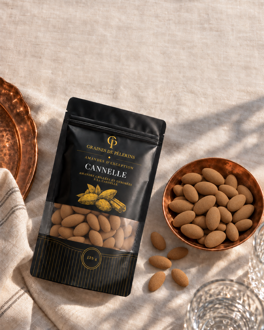 Bolsa y cuenco de Almendras con Canela vistos desde arriba, sobre lino y una bandeja cobriza.