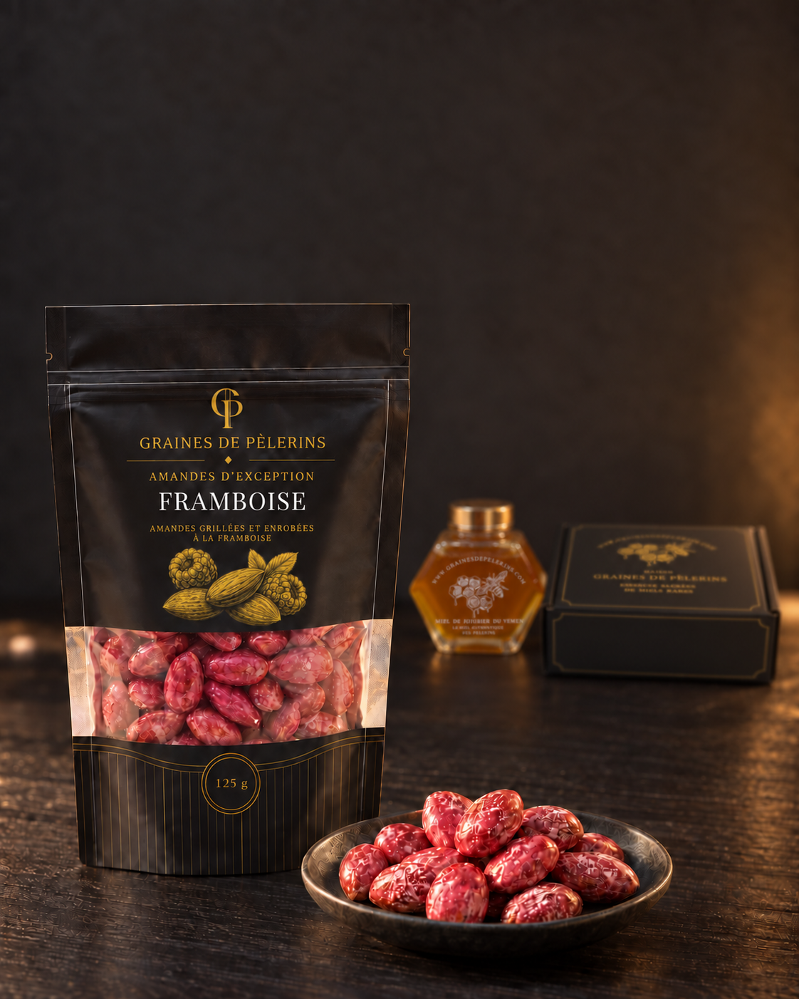 Bolsa y cuenco de almendras Frambuesa sobre madera oscura, con miel y un estuche negro y dorado al fondo.