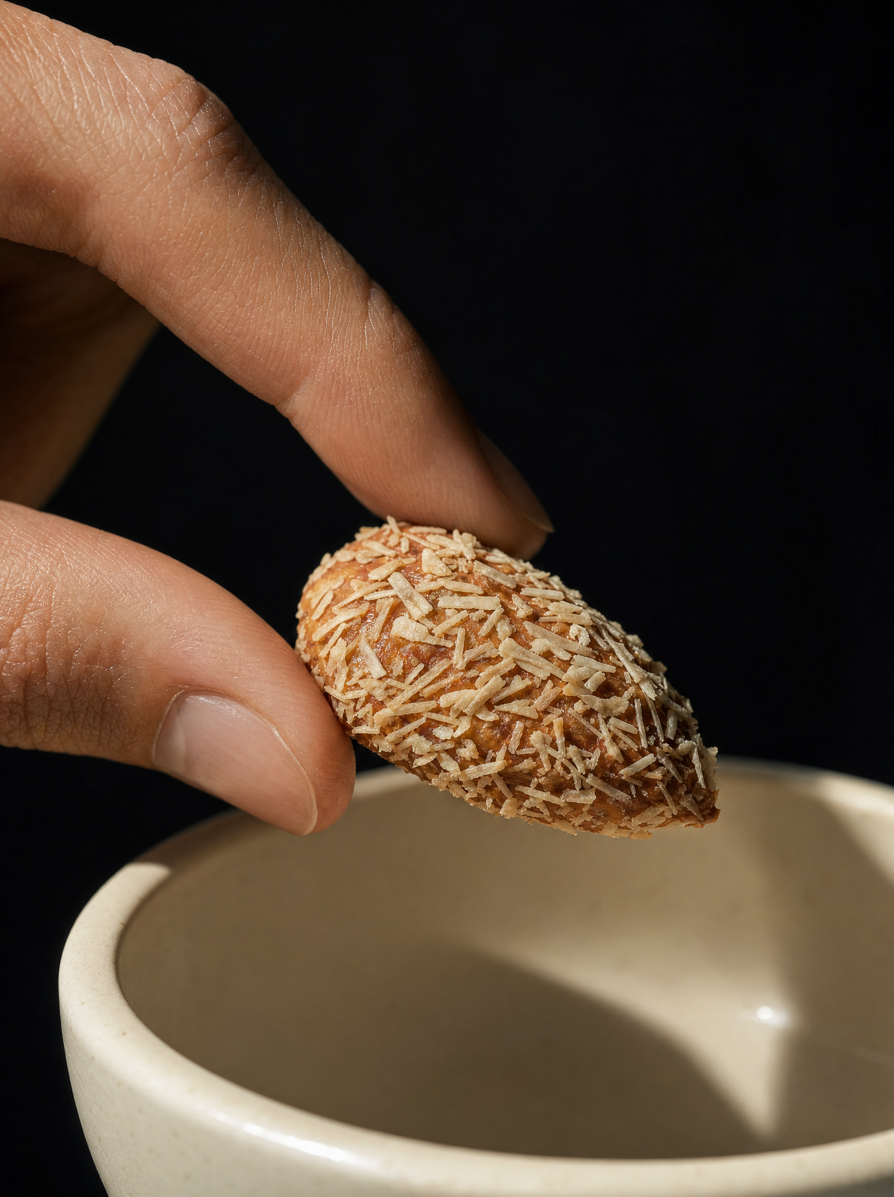 Amandes Noix de Coco présentées dans la main, relief caramel et éclats ivoire visibles